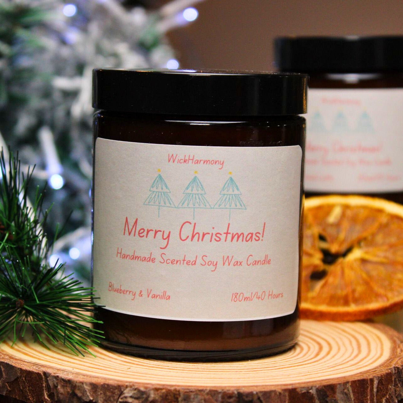 A 180ml Christmas soy candle with a minimalist three-tree label, shown with festive greenery and a dried orange slice