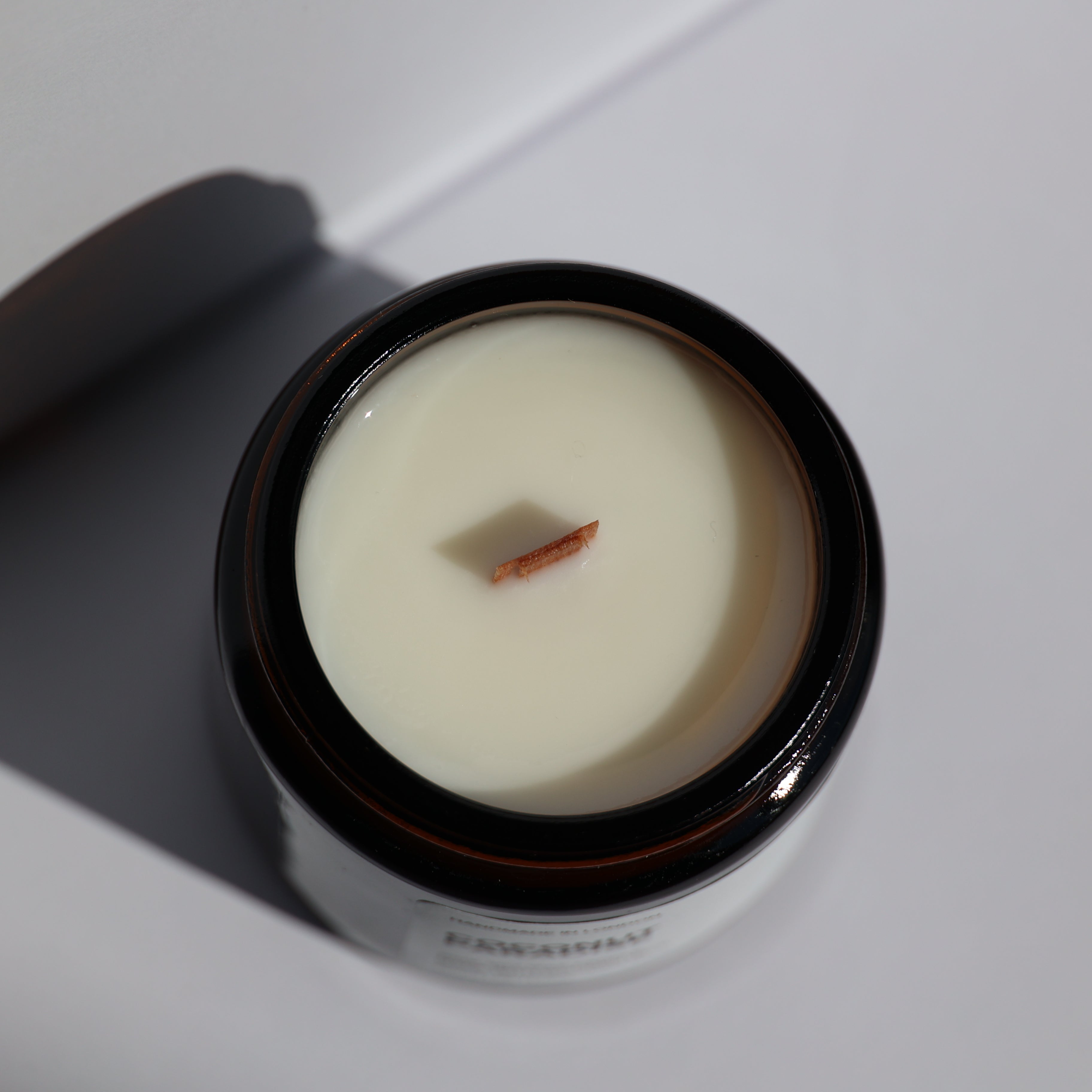 A top-down view of a 120ml candle, showing the cream-colored soy wax and the flat wooden wick inside the amber glass jar.