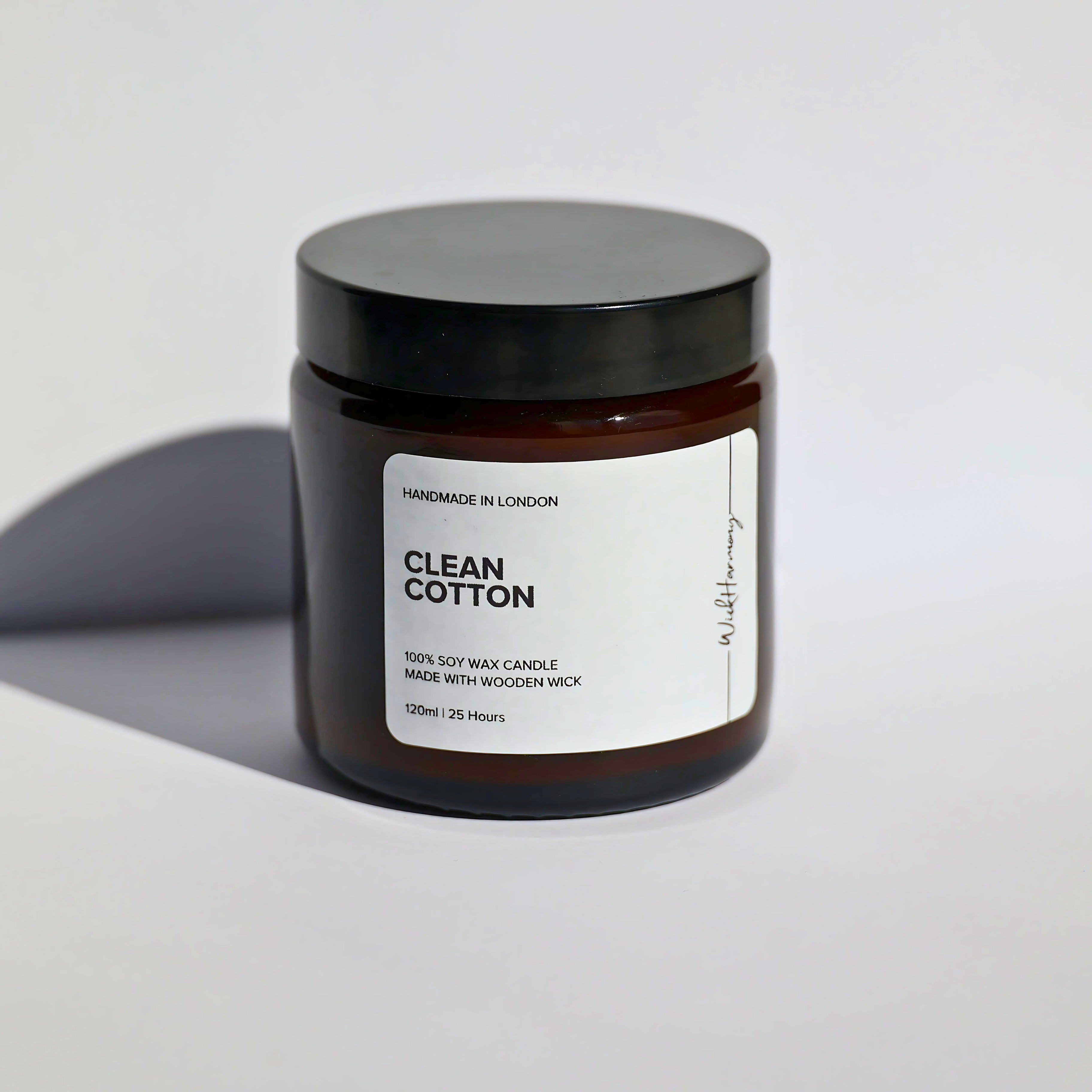 A 120ml amber jar 'Clean Cotton' soy wax candle by WickHarmony, shown in a studio product shot against a plain white background.
