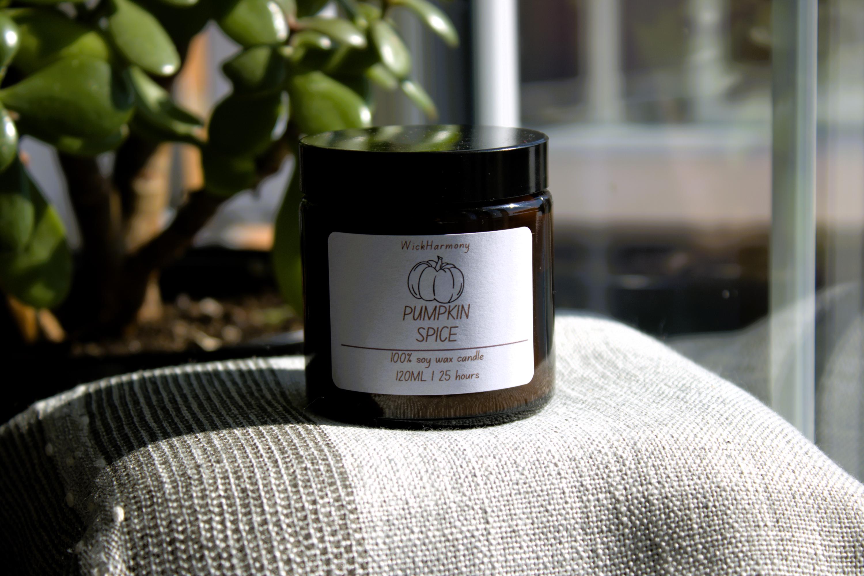 The Festive Doodle' soy wax candle sitting on a linen cushion in a bright, sunlit window