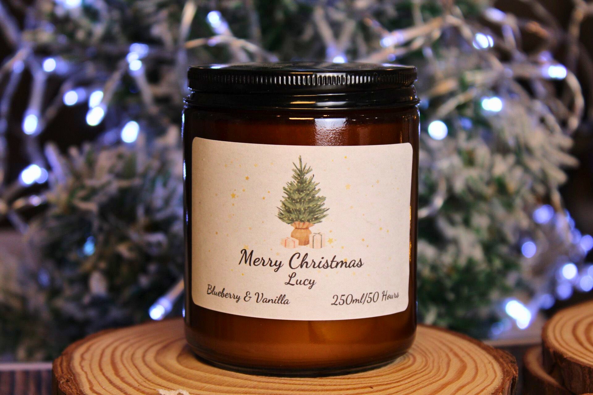 A large 250ml Blueberry & Vanilla scented candle with a personalised Christmas tree label on a wooden coaster.