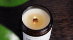 A lit wooden wick crackling with a soft, warm flame in a WickHarmony soy wax candle
