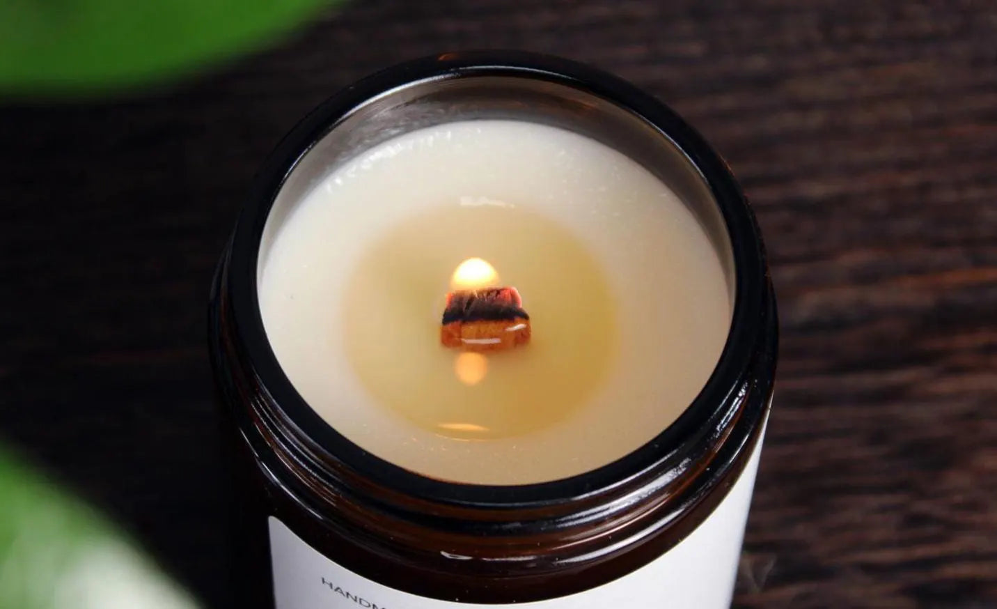 A lit wooden wick crackling with a soft, warm flame in a WickHarmony soy wax candle