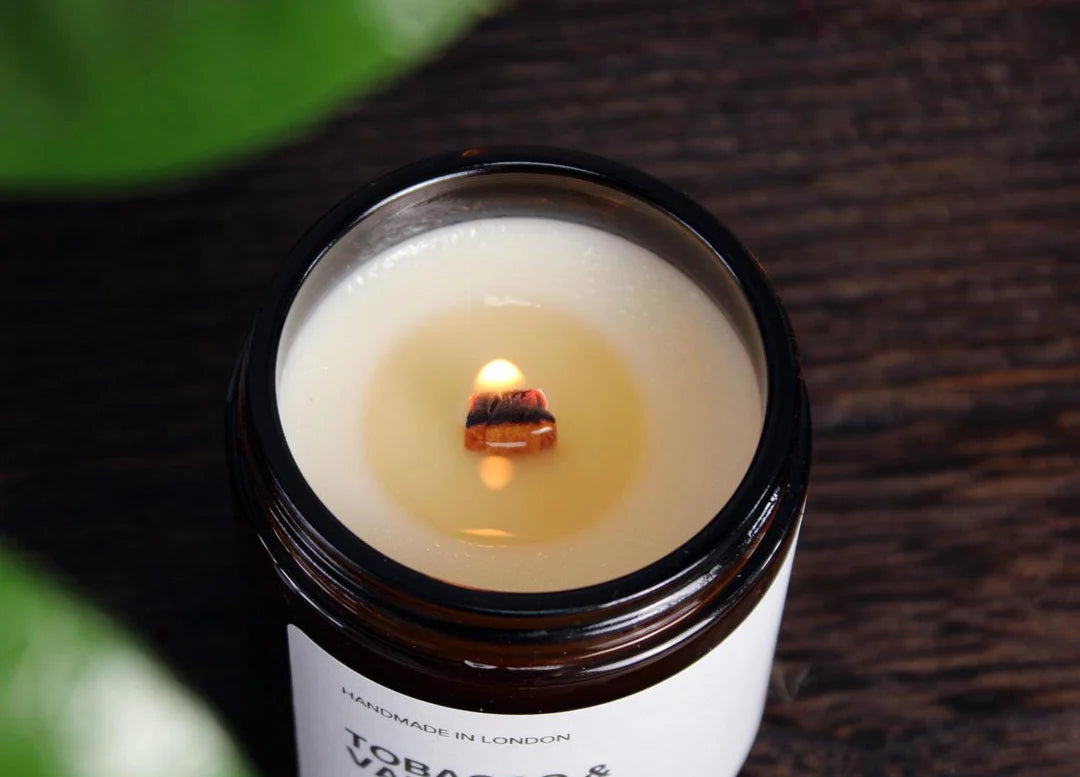 A close-up of a lit wooden wick crackling with a soft, warm flame in a WickHarmony soy wax candle