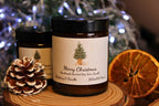 A medium 180ml personalised Christmas candle sitting next to a pinecone and a dried orange slice for a festive feel