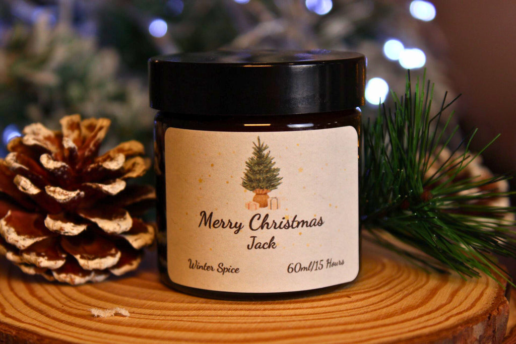 A small 60ml Winter Spice candle personalised with the name 'Jack' on a rustic wood slice with festive decor.