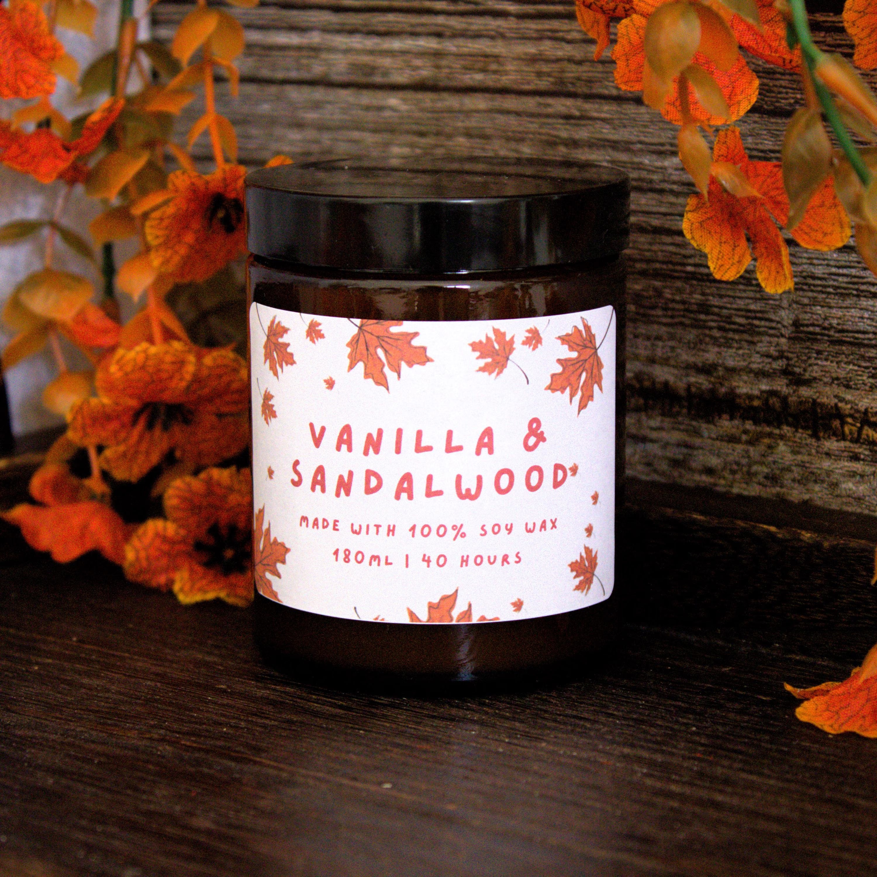 The 180ml 'The Rustic Script' candle by WickHarmony, styled in a cosy autumn setting against a dark wood background