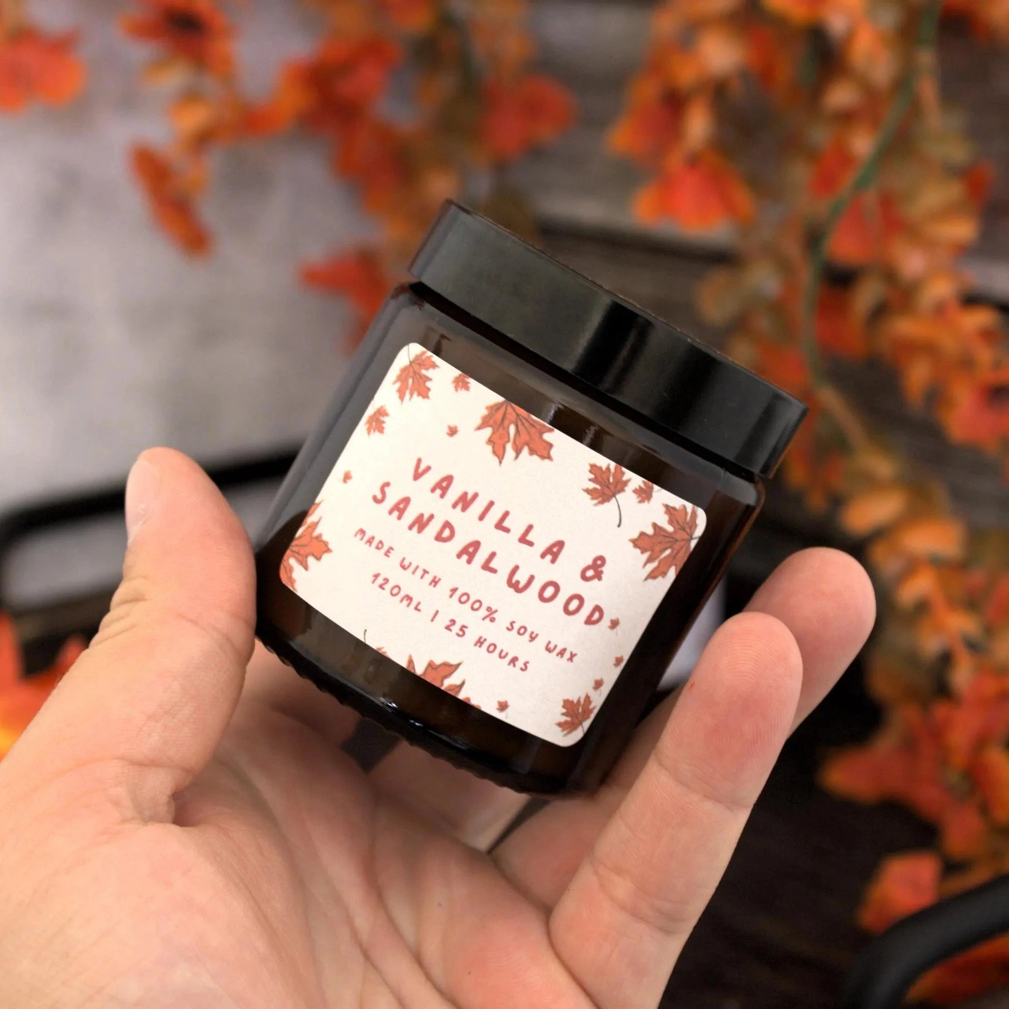 A person holding the 120ml 'The Rustic Script' soy candle to show its size and handmade label design