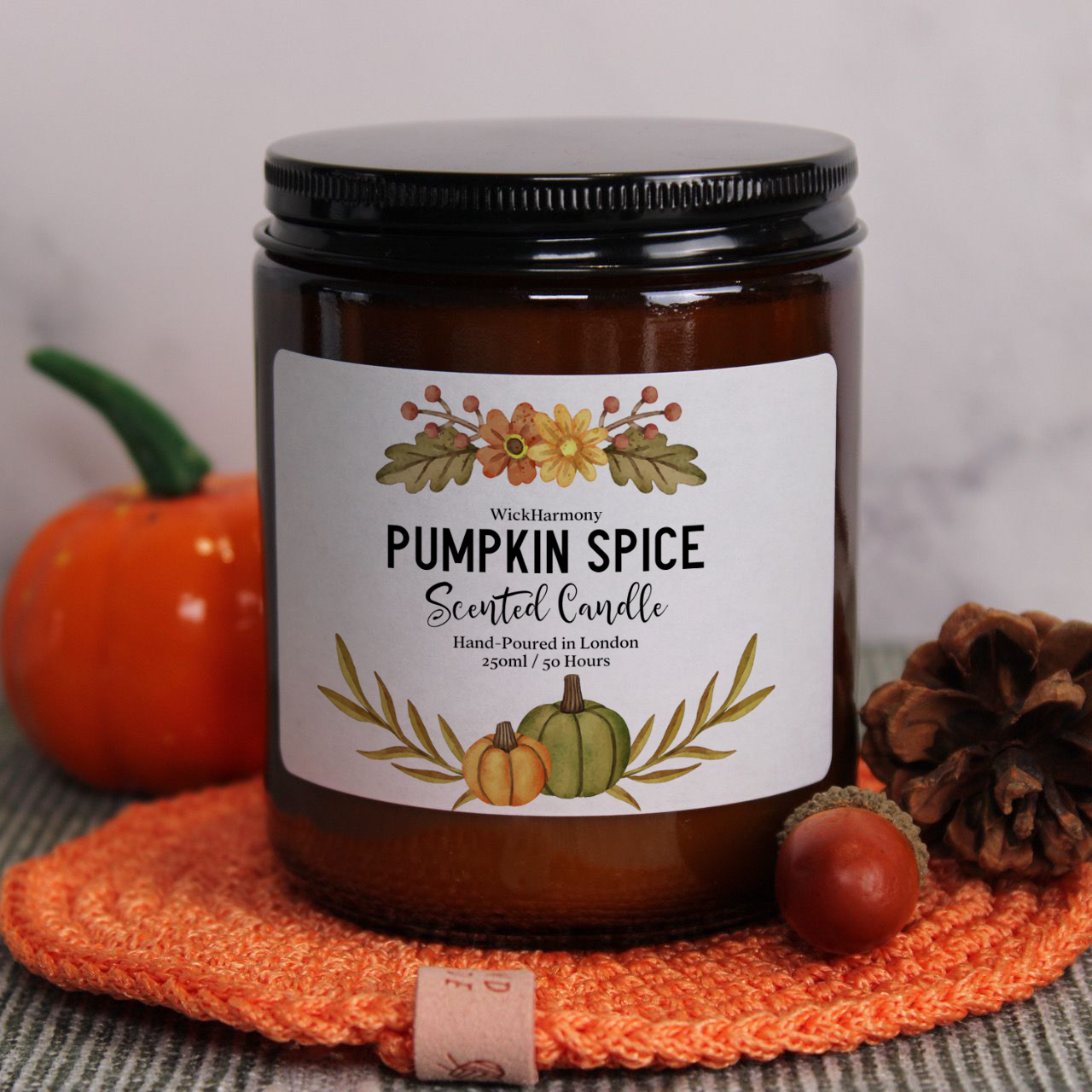 The 250ml 'Watercolour Harvest' candle by WickHarmony, featuring a pumpkin spice design and styled with a mini pumpkin and a pinecone