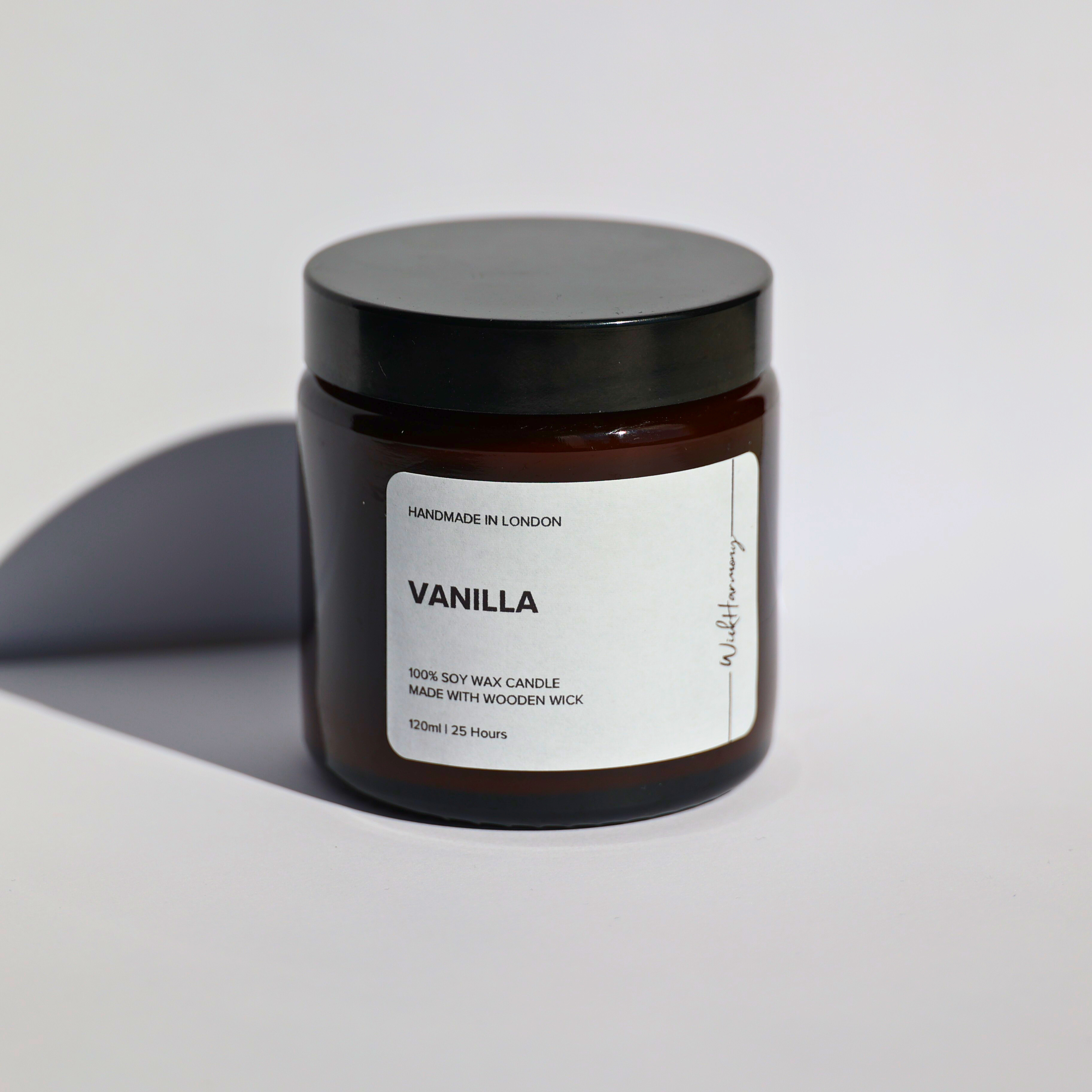 A studio product photo of the 120ml 'Vanilla' soy wax candle by WickHarmony, shown in an amber jar against a plain white background.