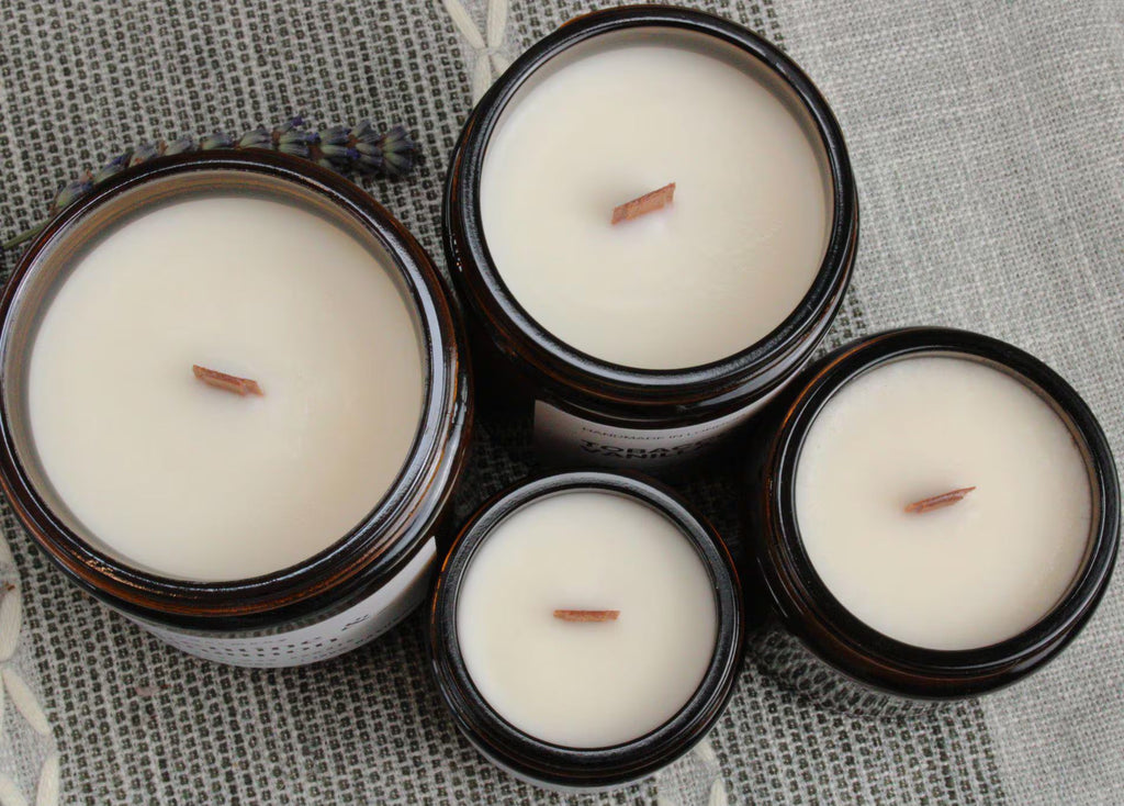 Top-down view of four WickHarmony soy wax candles in amber jars, showing the natural wooden wicks