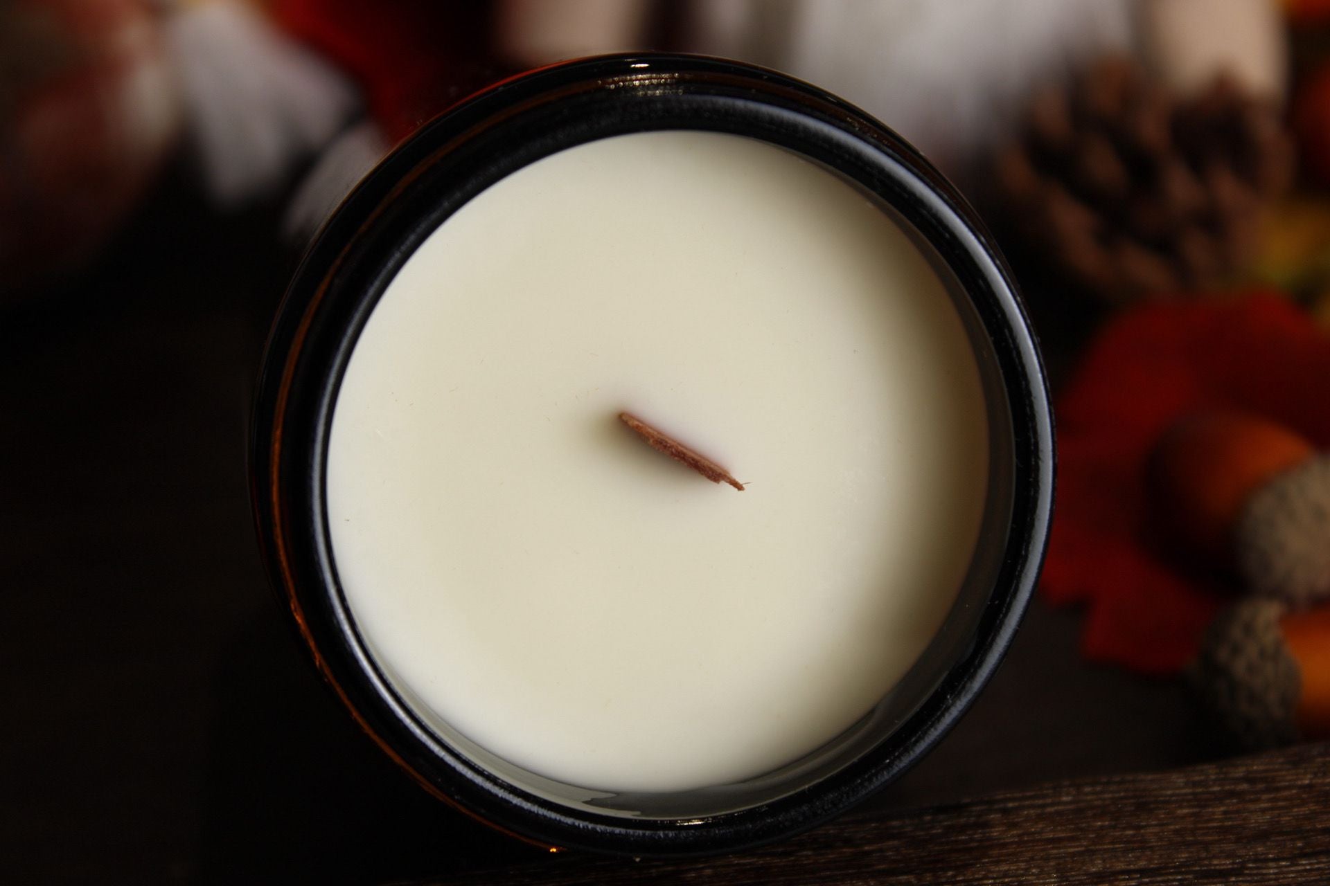 Top-down view of a WickHarmony soy wax candle in an amber jar, showing the natural wooden wick